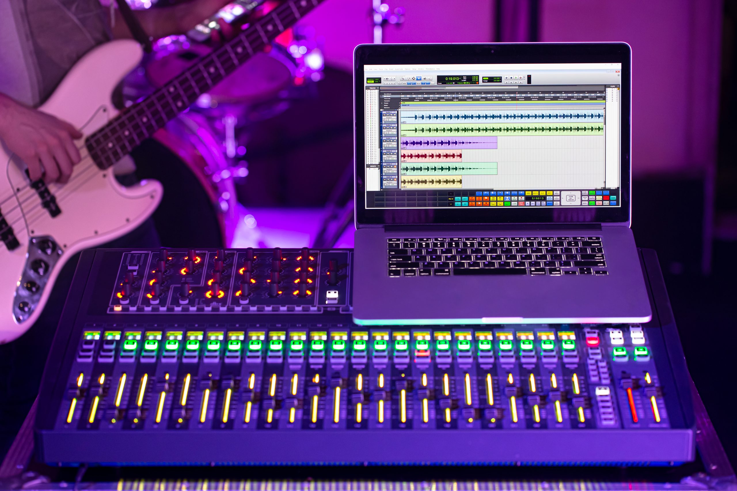 Digital mixer in a recording Studio , with a computer for recording music. On the background of a man with a bass guitar. The concept of creativity and show business.